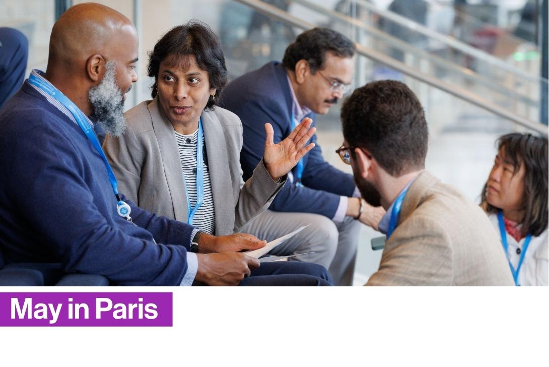 A group of business executives in a meeting, with a man in the foreground wearing a blue shirt and a woman in a gray blazer looking forward during Columbia Business School Executive Education’s The Business of AI program available in Paris, France, the school's only location in Europe.